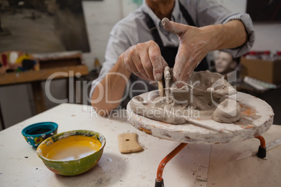 Mid-section of senior man molding clay