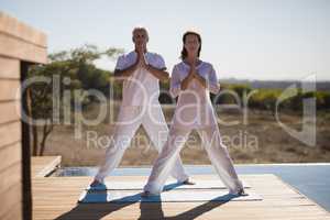 Couple practicing yoga on wooden plank