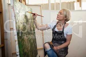 Attentive woman painting on canvas