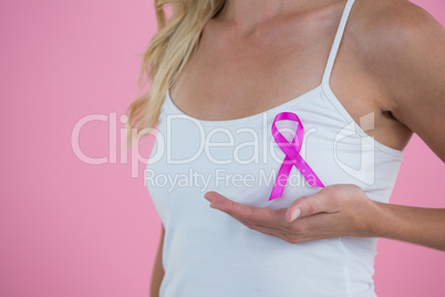 Mid section of woman with Breast Cancer Awareness ribbon on breast