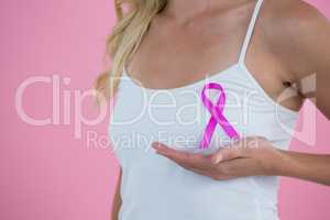 Mid section of woman with Breast Cancer Awareness ribbon on breast