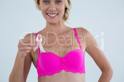 Smiling woman in pink bra showing Breast Cancer Awareness ribbon