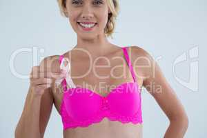 Smiling woman in pink bra showing Breast Cancer Awareness ribbon