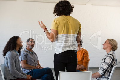 Man gesturing while discussing with friends sitting on chair