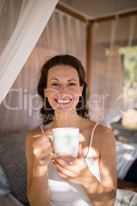 Portrait of happy woman having coffee in canopy bed