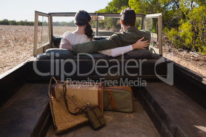 Rear view of couple with arms around in off road vehicle