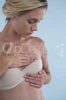 Young woman touching breast while checking for lumps