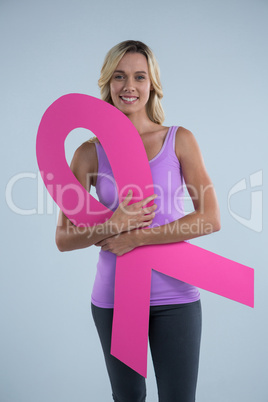 Portrait of young female holding cardboard Breast Cancer Awareness ribbon
