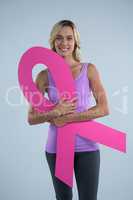 Portrait of young female holding cardboard Breast Cancer Awareness ribbon