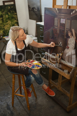 Attentive woman painting on canvas