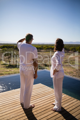 Couple standing near poolside looking at distance