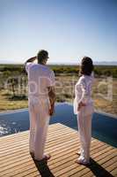 Couple standing near poolside looking at distance