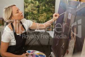 Attentive woman painting on canvas