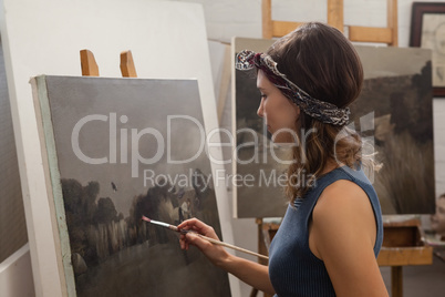 Woman painting on canvas in drawing class