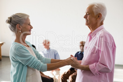 Senior friends looking at man and woman holding hands