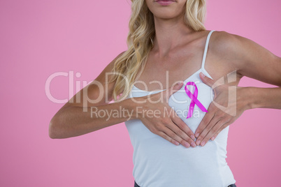 Mid section of woman showing Breast Cancer Awareness ribbon on breast