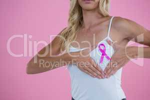 Mid section of woman showing Breast Cancer Awareness ribbon on breast