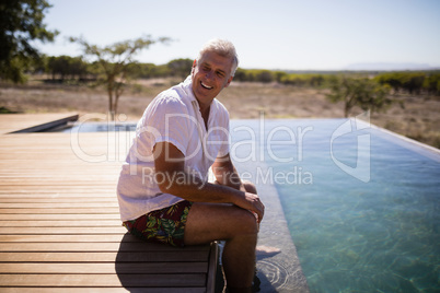 Smiling man sitting near pool side