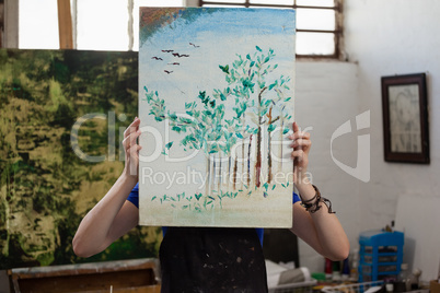 Woman hiding her face behind painting