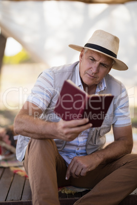 Attentive man reading book in cottage