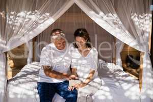 Happy couple using digital tablet on bed