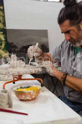 Attentive man molding clay