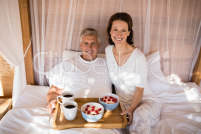 Happy couple having breakfast in canopy bed