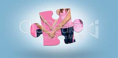 Composite image of mid section of women in pink outfits holding hands while standing for breast canc