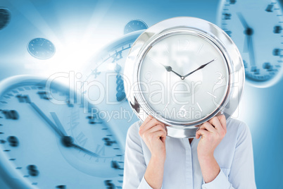 Composite image of businesswoman in suit holding a clock