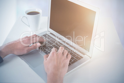 Composite image of cropped hands of businessman using laptop while having coffee