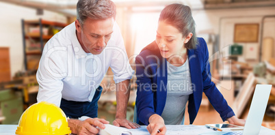 Composite image of female architect explaining blueprint to colleague