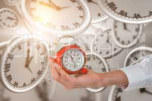 Composite image of cropped hand holding alarm clock