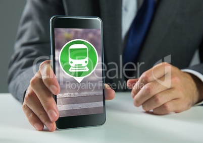 Hand holding phone with train icon on desk