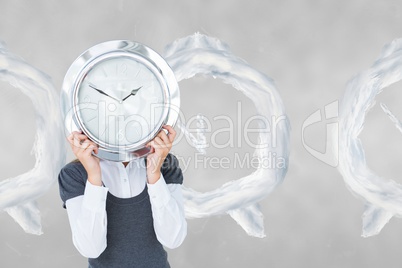 Woman holding a clock against background with clocks