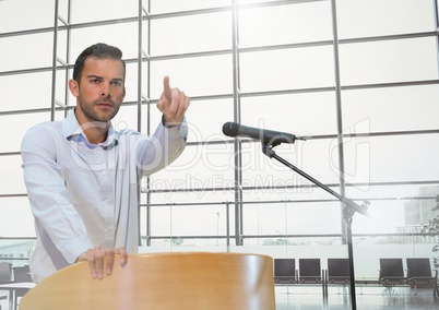 Businessman on podium speaking at conference with windows