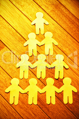 Paper cut out figures forming human pyramid on table