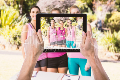 Composite image of cropped hand holding digital tablet