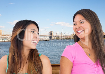 Best friends smiling at each other against water and skyline
