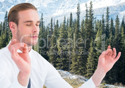 Business man meditating against trees and snowy mountain