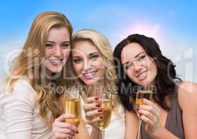 Three millennial women toasting against blurry sky