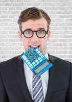 Close up of nerd man with blue calculator in mouth against white brick wall