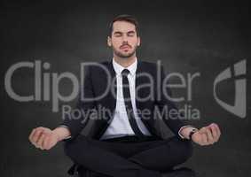 Business man meditating against grey wall