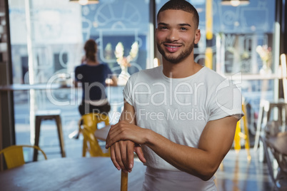 Portrait of waiter with customer in background at cafe