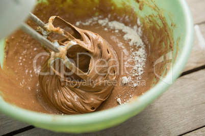 Overhead view of electric mixer mixing flour and chocolate batter in bowl