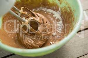 Overhead view of electric mixer mixing flour and chocolate batter in bowl