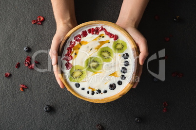 Hands holding a bowl of fruit cereal