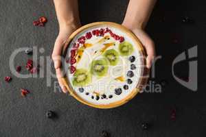 Hands holding a bowl of fruit cereal