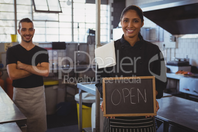 Portrait of waitress with open sign at cafe