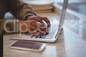 Cropped hands of businessman using laptop