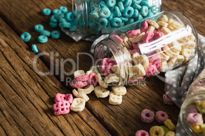 Scattered cereals from jar on wooden table